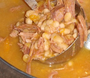 a ladle full of ham and bean pumpkin soup
