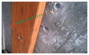 The pre-drilled holes in the cement and wood.