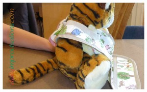 A side view of the baby bib on the cooperative stuffed tiger.