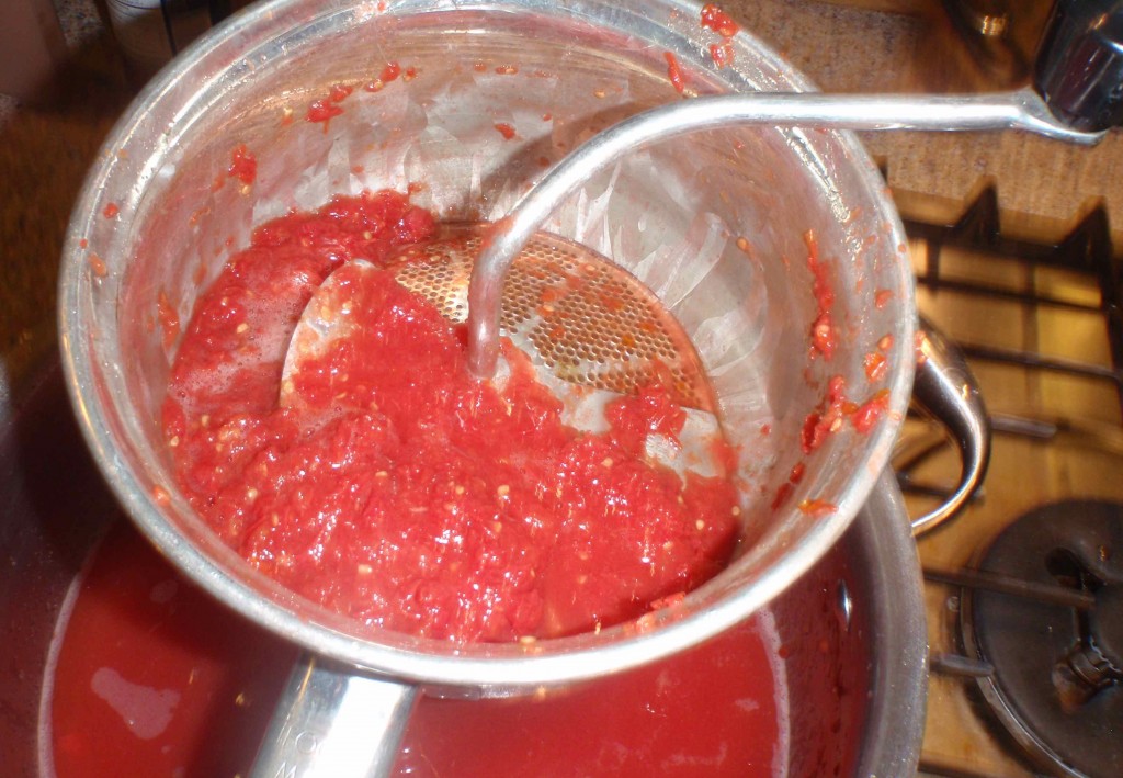 Here a basic food mill is being used to separate the tomato skins and seeds from the liquid; there is a bit more turning and back turning to do.